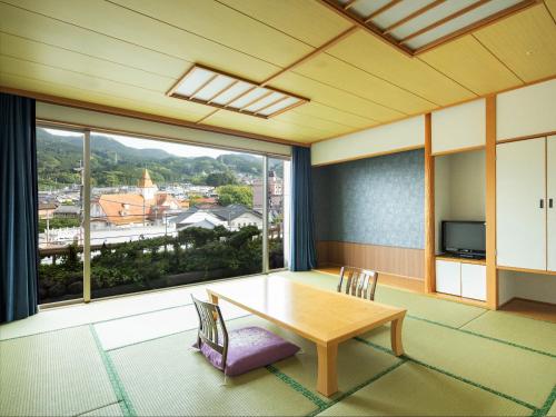 a room with a table and chairs and a large window at Hotel Sakura Ureshino in Ureshino