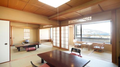 a living room with a table and a large window at Syukaen Yunohanazen in Atami