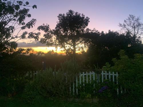 a sunset in a garden with a white fence at Cabaña Mamá Elia in Trinidad