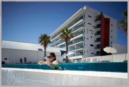 a woman standing in a swimming pool next to a building at Seashells Mandurah in Mandurah