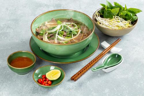 a bowl of soup sitting on a plate with chopsticks at The Oriental Jade Hotel in Hanoi