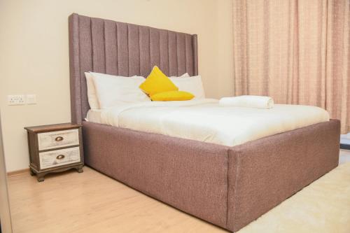 a bedroom with a large bed with yellow pillows at Elegant One Bedroom in Westlands in Nairobi