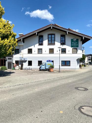 Un bâtiment blanc avec une voiture garée devant. dans l'établissement Hotel Egger-Stüberl, à Schechen