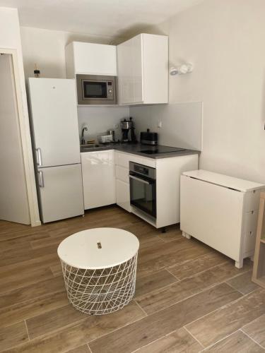 une cuisine avec des armoires blanches et une table à l'intérieur dans l'établissement Little garden, à Saint-Cyr-sur-Mer