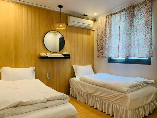 a bedroom with two beds and a mirror and a window at SSH LK Hostel in Seoul