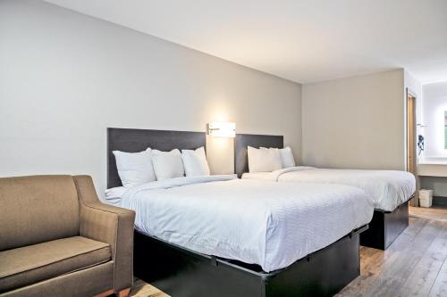a hotel room with two beds and a chair at Days Inn by Wyndham Augusta Fort Eisenhower in Augusta