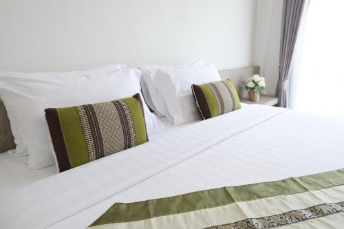 a white bed with three pillows on it at Baan Kieng Tawan in Khong Chiam
