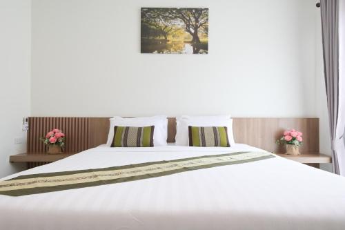 a bedroom with a large white bed with pink flowers at Baan Kieng Tawan in Khong Chiam