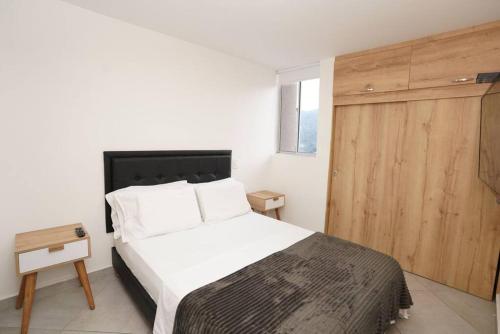 1 dormitorio con cama blanca y puerta de madera en Apartamento Medellin-sabaneta a cuadra del metro, en Sabaneta