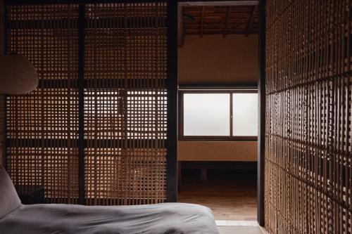 a room with a bed and a wall with a window at Maana Kiyomizu in Gionmachi