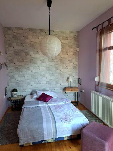 1 dormitorio con cama y pared de ladrillo en Mediterrán apartman en Pécs