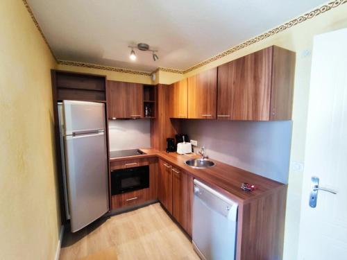 une cuisine avec des armoires en bois et un réfrigérateur en acier inoxydable dans l'établissement Appartement cosy proche pistes avec parking - FR-1-292-195, à Isola