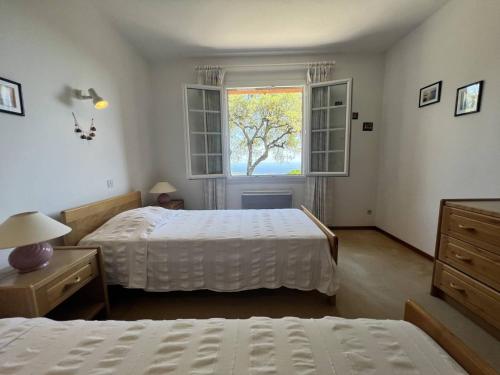 une chambre avec deux lits et une fenêtre dans l'établissement Villa de charme avec piscine privée, climatisation, BBQ, calme absolu - FR-1-726-11, à La Croix-Valmer