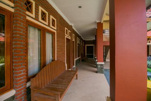 a wooden bench sitting on the side of a building at Hotel O Edotel Smkn 1 Pacet Syariah in Puncak