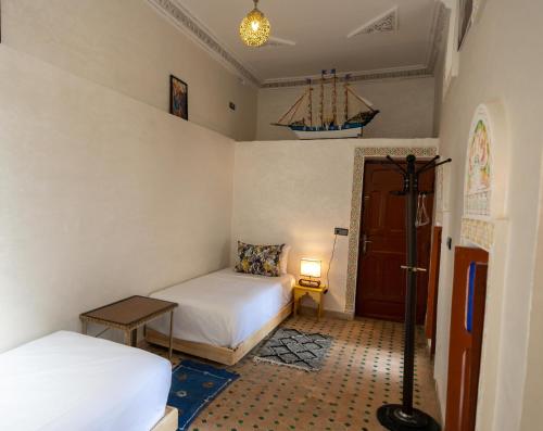 a bedroom with two beds and a door with a lamp at Riad Tarab Fes in Fès
