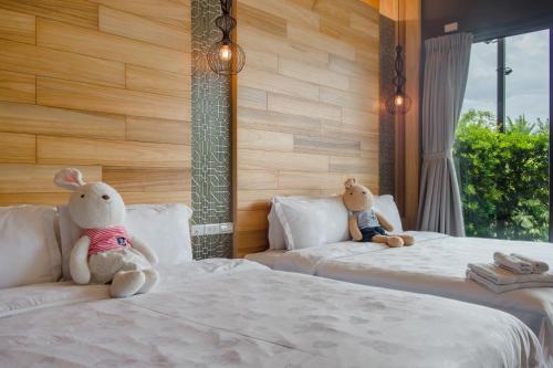 two stuffed animals sitting on two beds in a room at Jiaoxi 320 B&B in Jiaoxi
