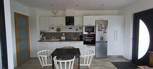 a kitchen with white cabinets and a table and chairs at Studio 1 Cabana de pe Stanca in Colibiţa