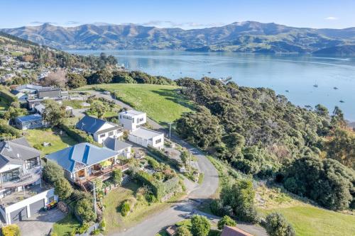 an aerial view of a house on a hill next to a lake at Harbour Views - Akaroa Holiday Home in Akaroa