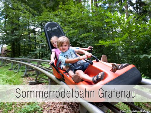 two young children riding on an orange bumper train at Hütte40: Ganze Hütte nah am See mit privatem Whirlpool, Sauna. Umzäunt. in Waldkirchen