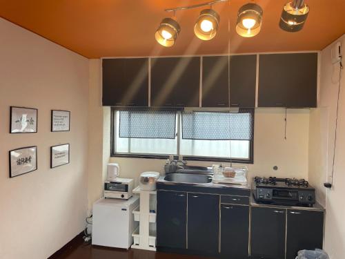 a kitchen with black cabinets and a sink and a window at 777 Takamatsu Guest House in Takamatsu