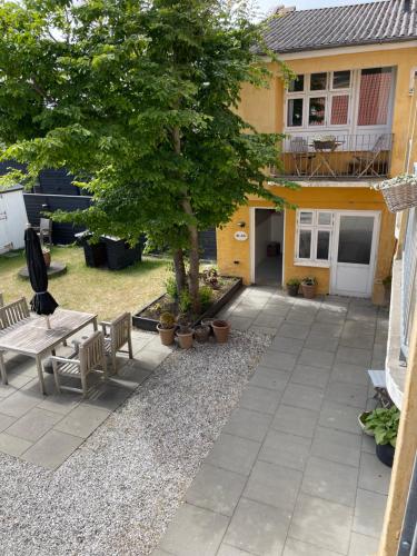 a patio with a tree and benches in front of a house at Kallehavegaard Badehotel in Løkken