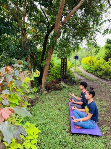 two men sitting on a yoga mat in the grass at Shanti Wellness Sanctuary in Lemery
