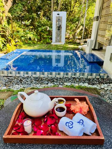 a tray with a tea pot and flowers on a table near a pool at Shanti Wellness Sanctuary in Lemery