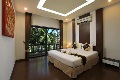 a bedroom with a large bed and a large window at Rawai Grand House -SHA Plus in Rawai Beach