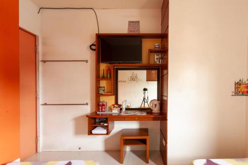 a room with a desk with a mirror and a television at TERRA: Grove area, 2 min walk to UPLB Gate in Los Baños