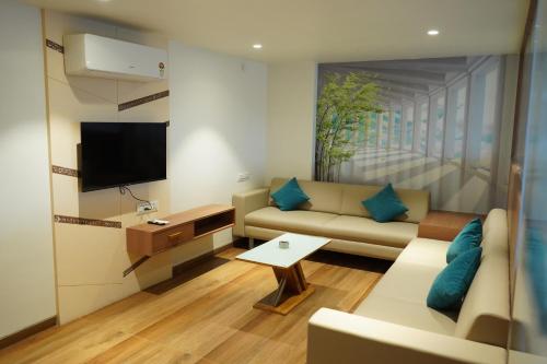 a living room with a couch and a tv at HOTEL OM INN in Gandhinagar