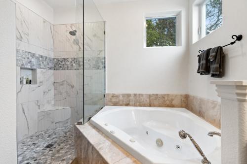 La salle de bains blanche est pourvue d'une baignoire et d'une douche. dans l'établissement Gorgeous Santa Cruz Villa - Modern Beachside Paradise with NEW Hot Tub & Fast Wi-Fi, à Santa Cruz