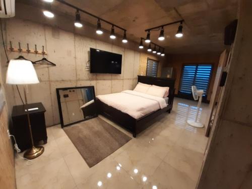 - une chambre avec un lit, une télévision et des lumières dans l'établissement Soo Stay, à Seogwipo
