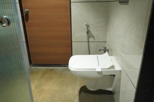 a bathroom with a white toilet and a shower at HOTEL OM INN in Gandhinagar