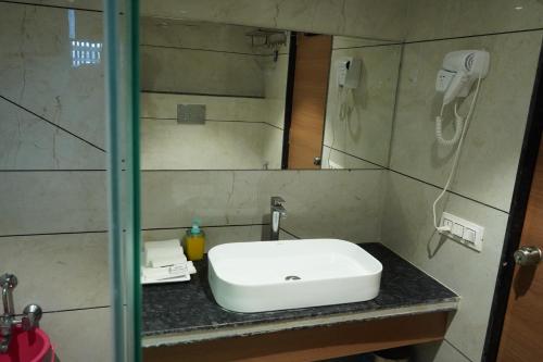 a bathroom with a white sink and a mirror at HOTEL OM INN in Gandhinagar