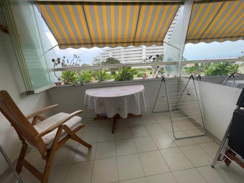un balcon avec une table, des chaises et une fenêtre dans l'établissement Marina baie des anges, beach downstairs, charming apartment with sea and garden view, à Villeneuve-Loubet