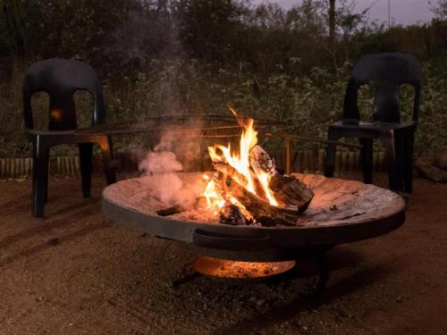 a fire pit with two chairs in front of it at Impala Cottage in Hoedspruit