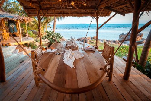 a wooden table on a wooden deck with a view of the ocean at Somewhere Only We Know in Baan Khai