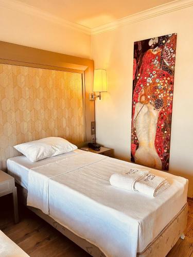 ein Schlafzimmer mit einem großen Bett und einem Gemälde an der Wand in der Unterkunft FİFTY5 SUİTE HOTEL in Marmaris