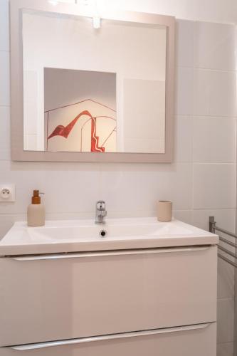 une salle de bain blanche avec un lavabo et un miroir dans l'établissement L'Atelier d'Artiste - refuge bohème et créatif, à Toulon