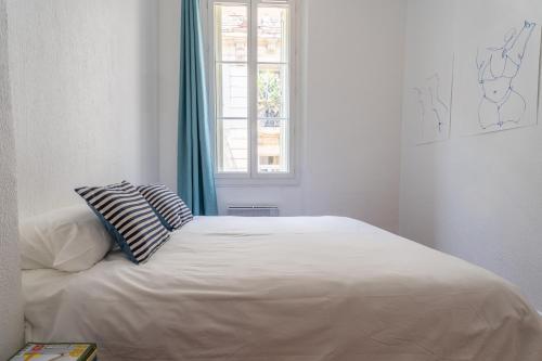 a white bed in a room with a window at L'Atelier d'Artiste - refuge bohème et créatif in Toulon