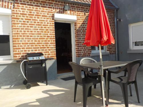 - une table avec des chaises et un parasol rouge sur la terrasse dans l'établissement 618 rue de l argiliere Helfaut 62570, à Helfaut