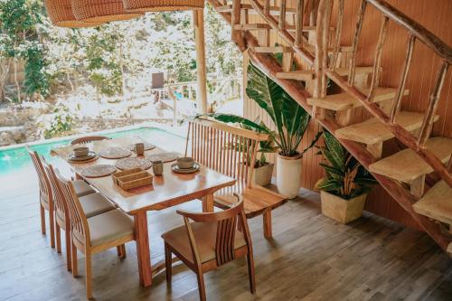 ein Esszimmer mit einem Tisch und Stühlen sowie einer Wendeltreppe in der Unterkunft Mayana By Blue Space in Banlot