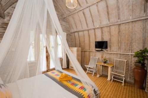 a bedroom with a bed with a mosquito net at The Mel Huts in Nusa Penida