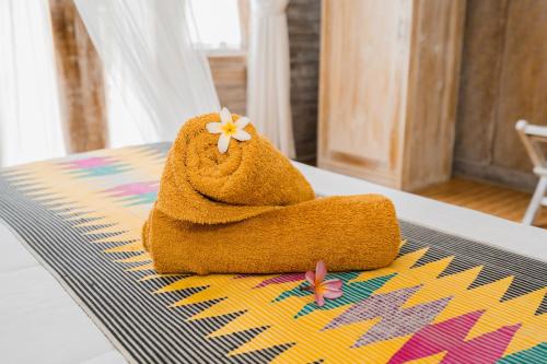 a towel with a flower on it sitting on a table at The Mel Huts in Nusa Penida