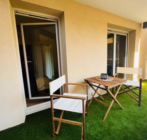 2 chaises et une table sur une terrasse avec pelouse dans l'établissement # Charme, Calme & Cosy # Brive #, à Brive-la-Gaillarde