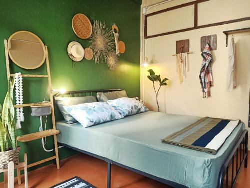 a bed in a room with a green wall at Be Local BNB in Bangkok