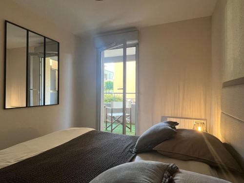 1 dormitorio con cama con espejo y ventana en # Charme, Calme & Cosy # Brive #, en Brive-la-Gaillarde