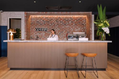 a woman standing at a counter with a brick wall at Veriu Collingwood in Melbourne