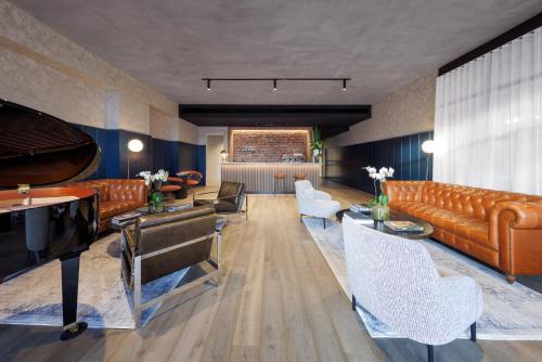 a living room with leather furniture and a piano at Veriu Collingwood in Melbourne