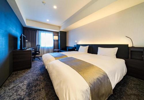 a hotel room with a large bed and a desk at Daiwa Roynet Hotel Koriyama Ekimae in Koriyama